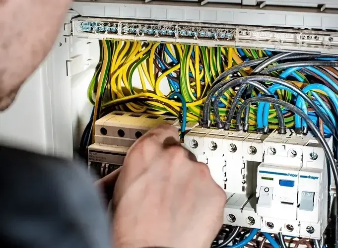 Elektriker som felsöker i ett öppet elskåp med automatsäkringar och kablage